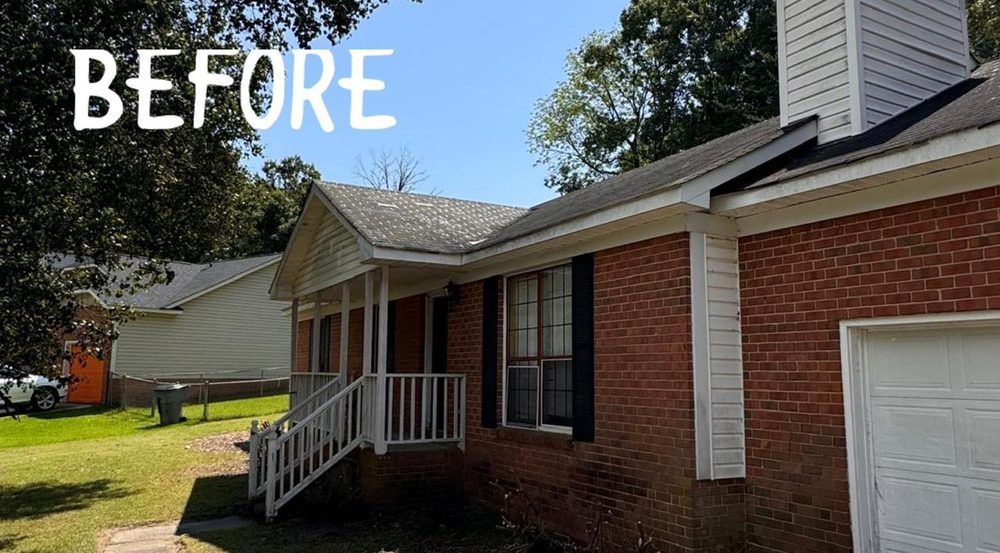 A red brick ranch house before renovation, with a worn roof and white porch railings