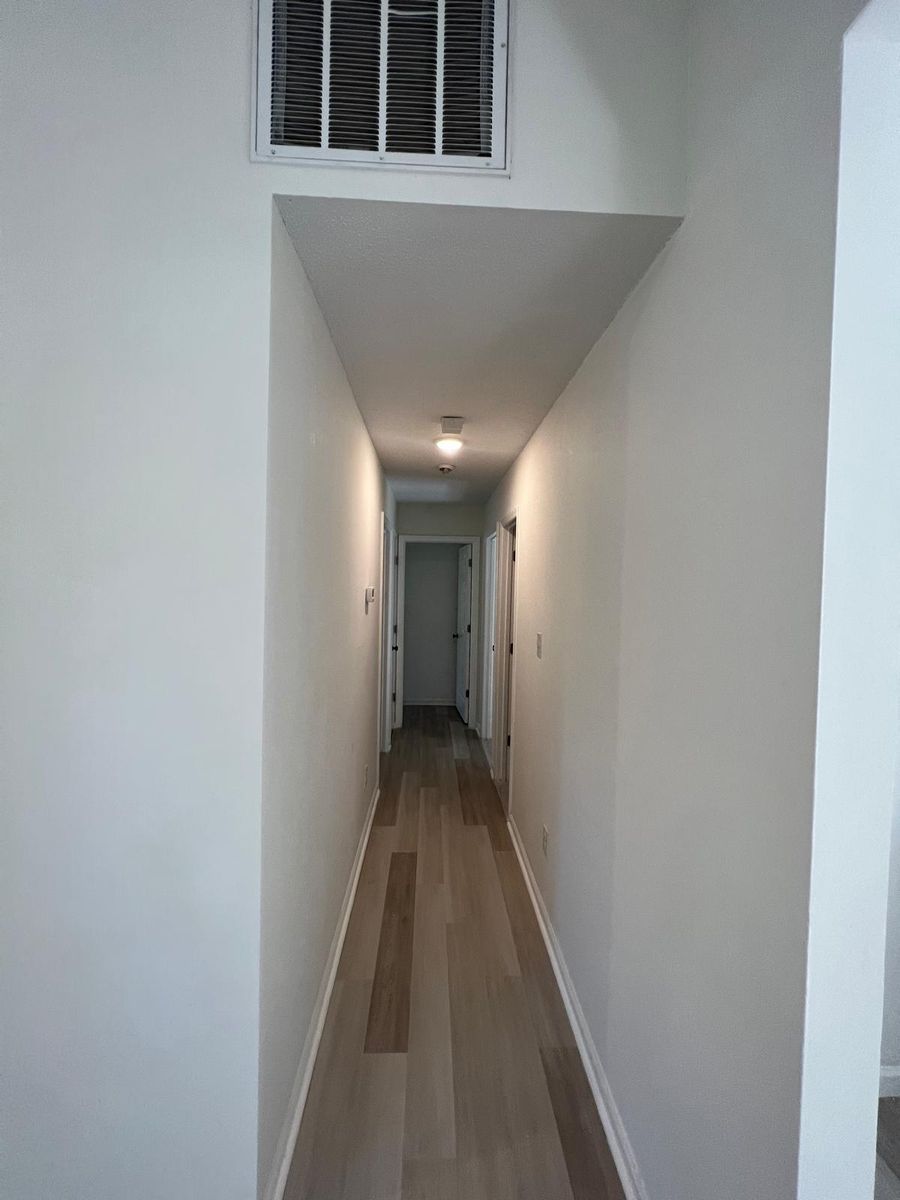 The hallway after renovation: fresh white walls, new trim, and wood-look plank flooring