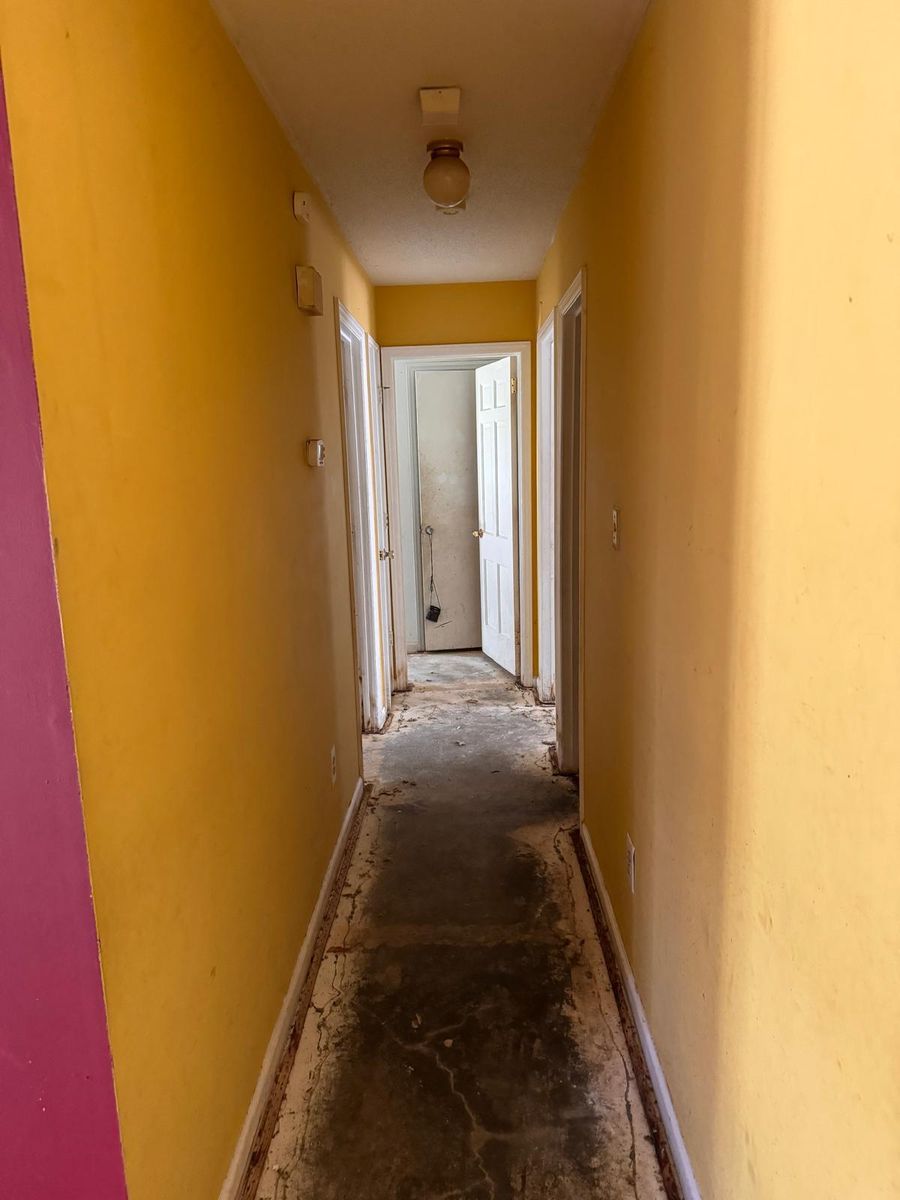 The hallway before renovation: bright yellow walls and a stained, bare floor